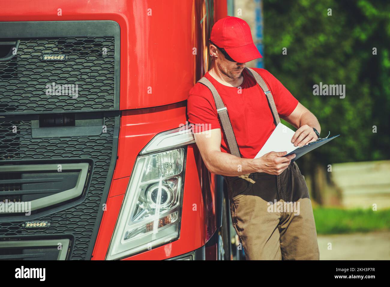 Professionista caucasico Trucker revisione dei documenti di spedizione del carico prima di iniziare la strada. Tema dell'industria dei trasporti. Foto Stock