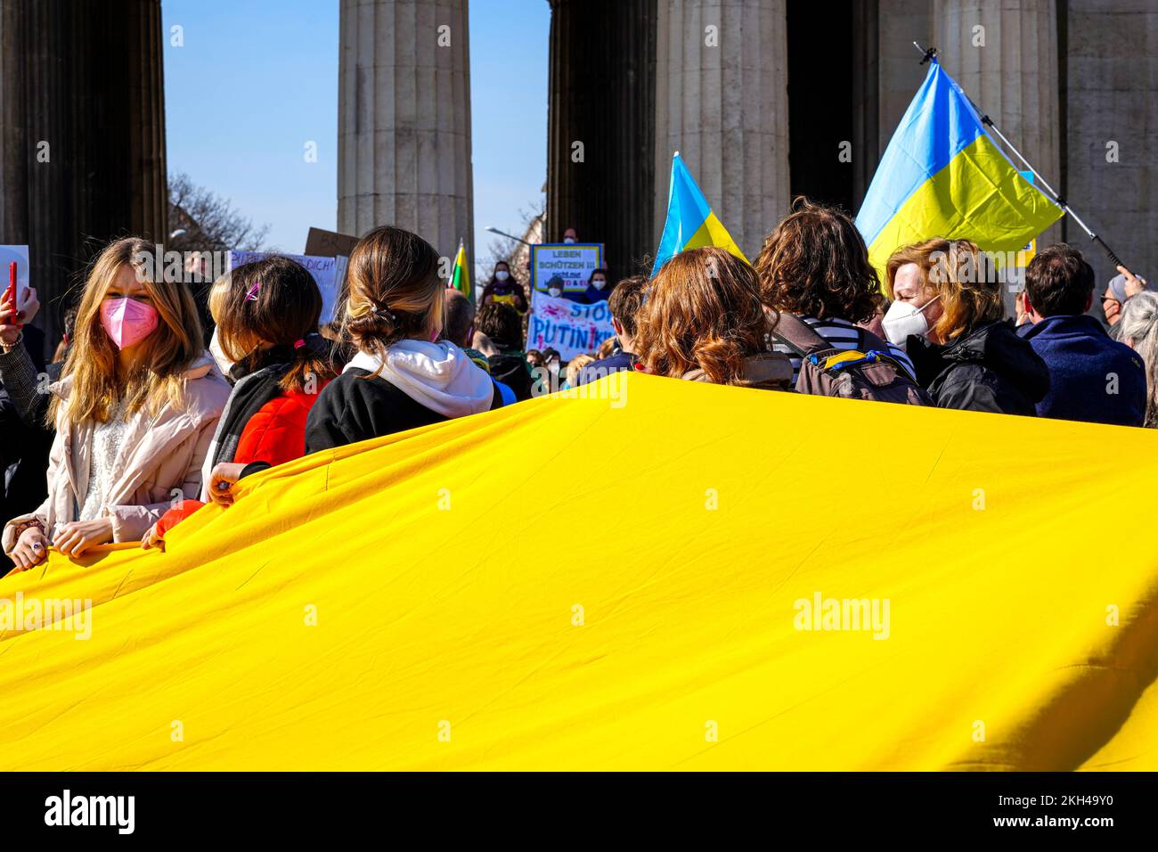 Durante una manifestazione contro la guerra russa in Ucraina, la gente porta con sé una grande bandiera Ucraina. Foto Stock