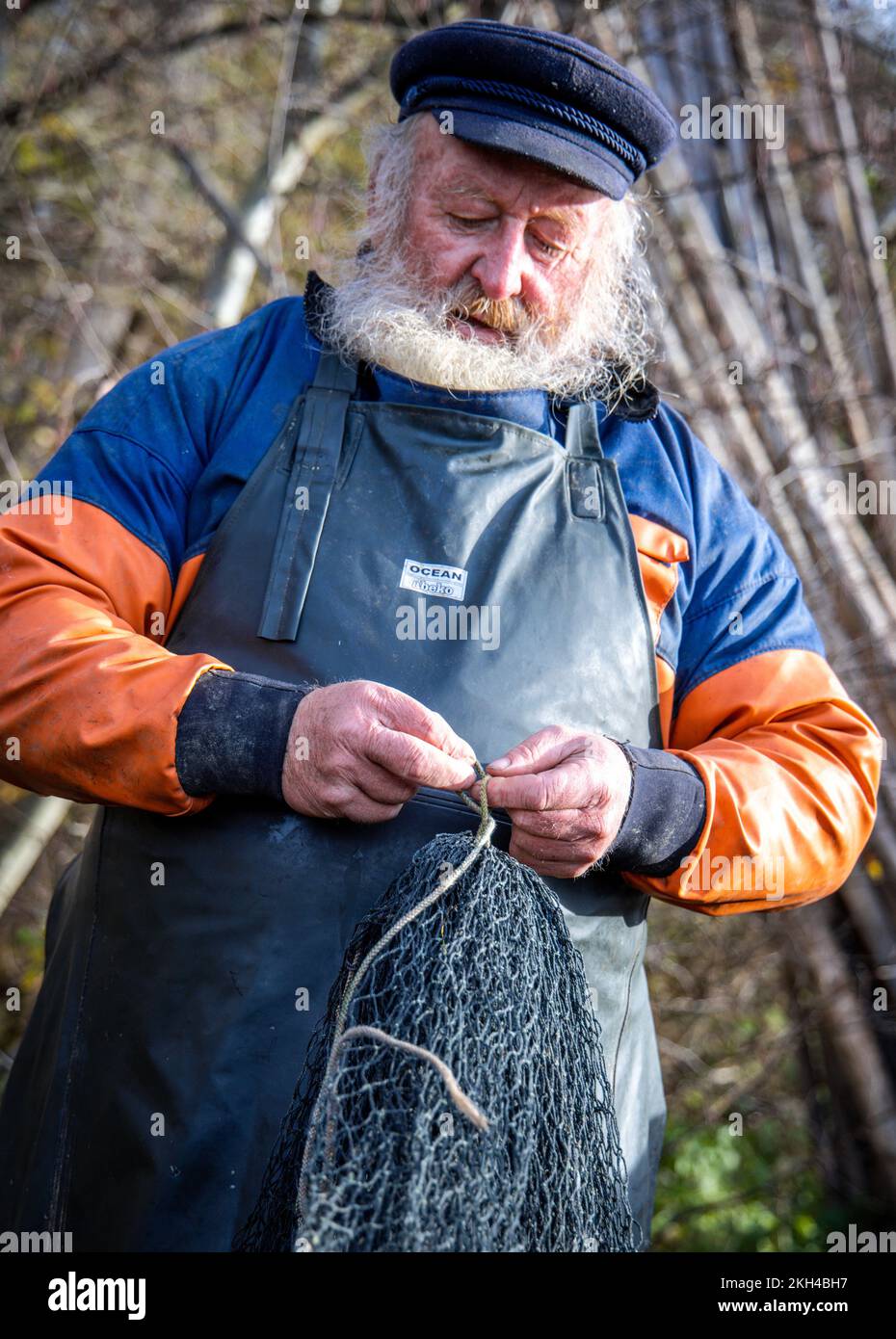Alt Schlagsdorf, Germania. 19th Nov 2022. Il pescatore Walter Piehl prepara la rete di trasporto al lago Neuschlagsdorf. Tre settimane dopo l'inizio della stagione delle carpe, tuttavia, le carpe natalizie non sono ancora entrate in rete nel Meclemburgo; solo la carpa e il luccio d'erba stanno battendo sugli attrezzi da pesca. Il tempo è troppo caldo e i pesci sono ancora troppo agili. Walter Piehl, un ex pescatore d'altura di 65 anni, è uno dei pochissimi pescatori del Meclemburgo-Pomerania occidentale che catturano carpe con reti da traino nei laghi naturali. Credit: Jens Büttner/dpa/Alamy Live News Foto Stock