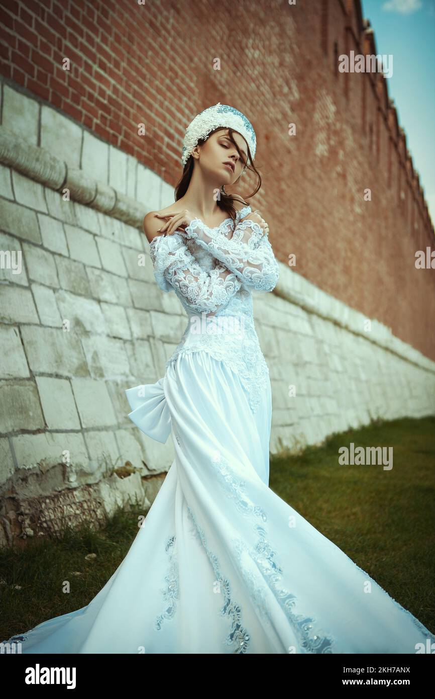 una ragazza in un lungo abito da sposa e un kokoshnik vicino ad un vecchio  muro. zaritsa russa Foto stock - Alamy