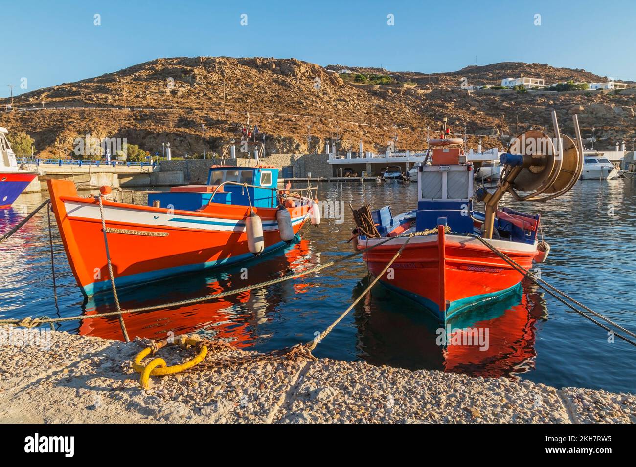Piccole barche da pesca greche tradizionali arancioni, bianche e blu con parabordi attraccati nel nuovo porto di Mykonos all'alba, isola di Mykonos, Grecia. Foto Stock