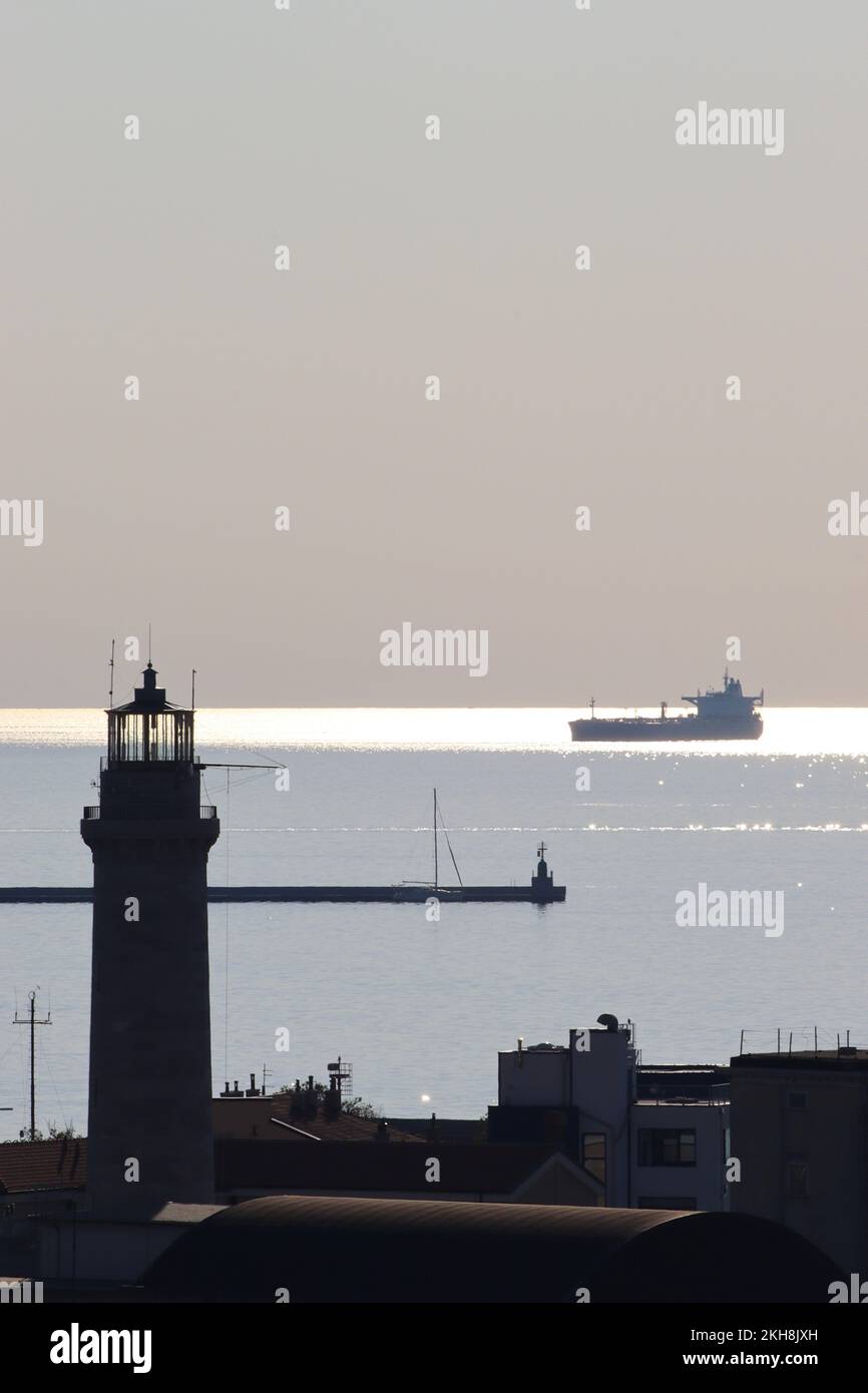 Luce notturna sul porto di Trieste e sul faro della Lanterna di Trieste, che trasforma elementi visibili in silhouette. Foto Stock