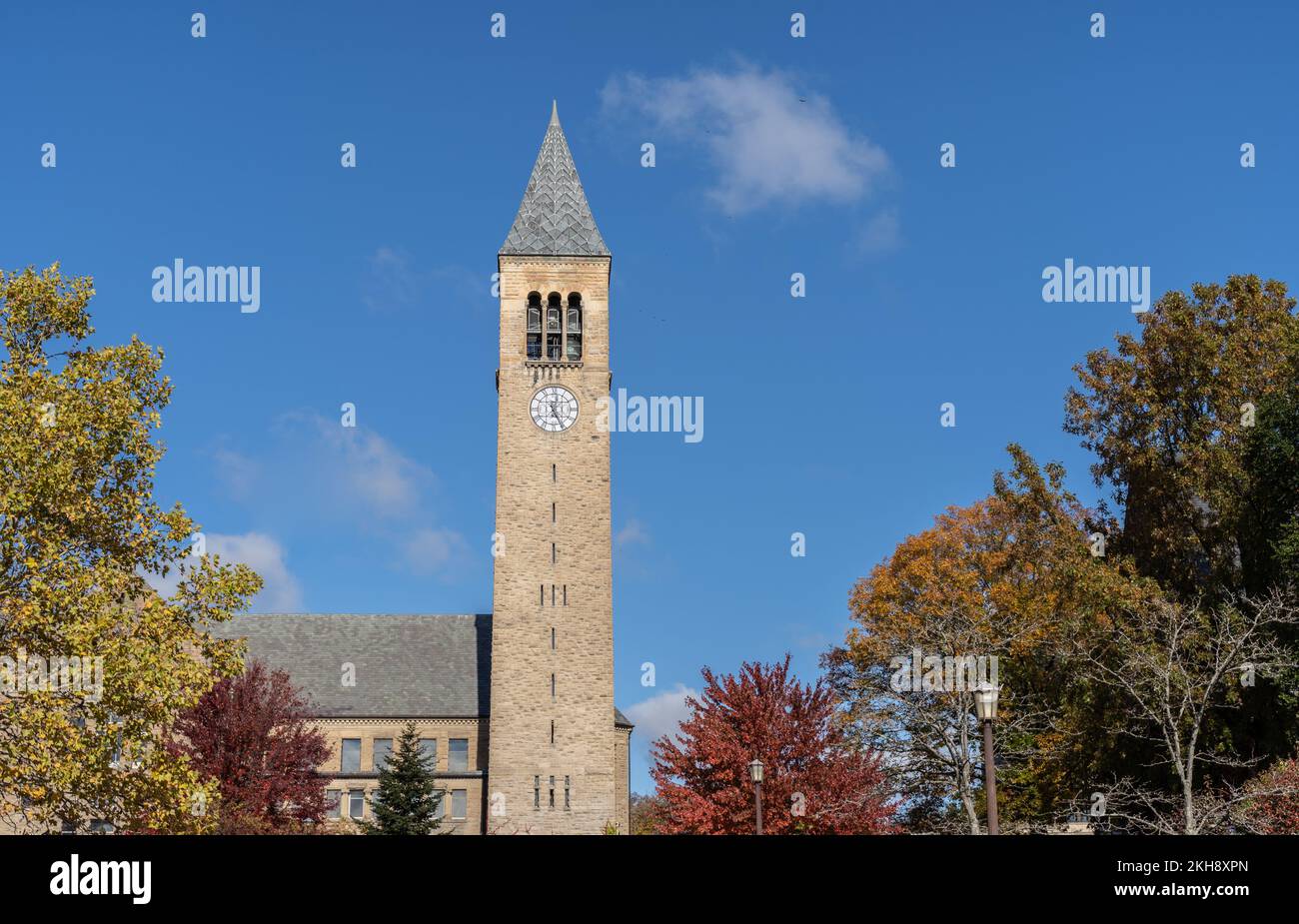 Ithaca, New York-24 ottobre 2022: McGraw Tower con un cielo blu e uno sfondo fogliare autunnale nel campus della Cornell University Foto Stock