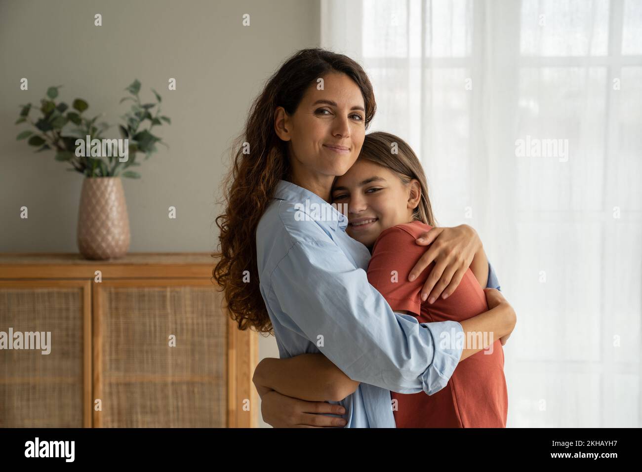 Gentile ottimista donna spagnola abbracciando sorridente ragazza adolescente che accetta congratulazioni per il giorno della madre Foto Stock