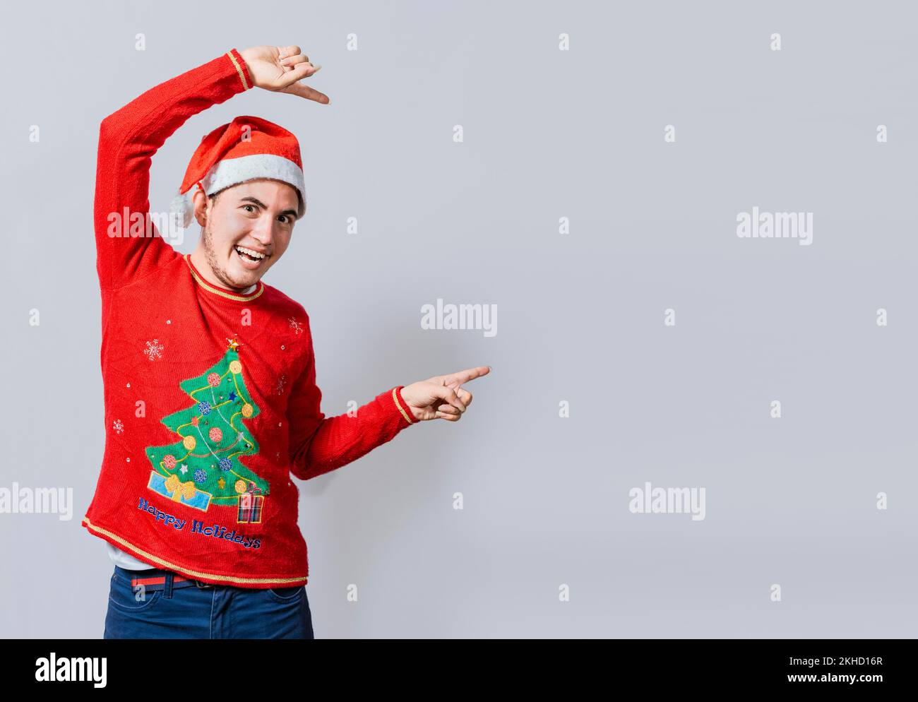 Amichevole uomo di Natale che indica uno spazio al lato. Un giovane sorridente amichevole nei vestiti di natale che indica un promo, un co allegro dell'uomo di natale Foto Stock