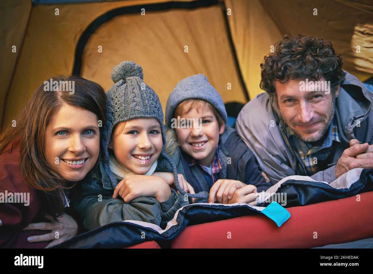 Felici campeggiatori. Ritratto di famiglia sorridente di quattro persone che si rilassano all'interno della tenda in un campeggio. Foto Stock