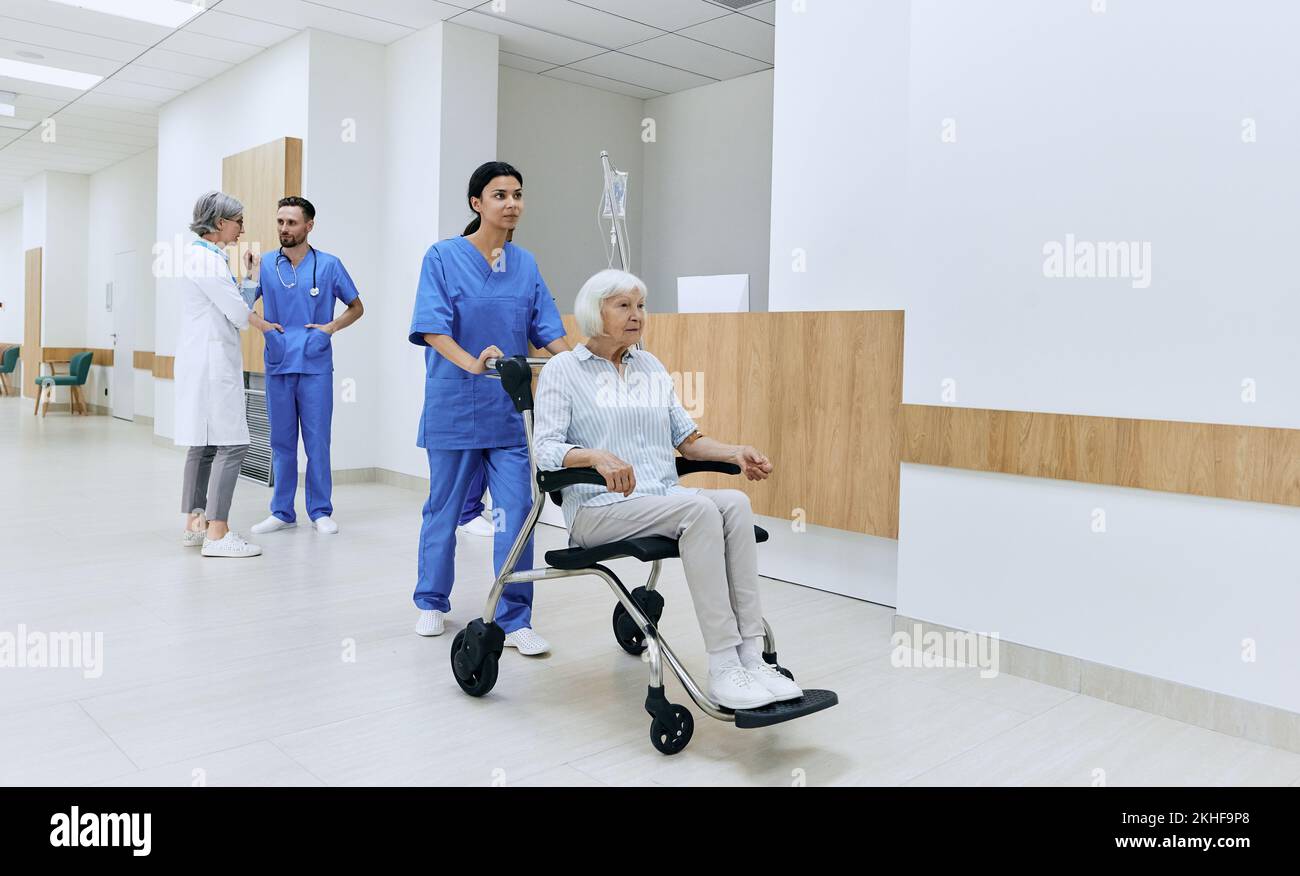 Infermiera asiatica che si prende cura di una donna anziana disabile seduta in sedia a rotelle in ospedale Foto Stock