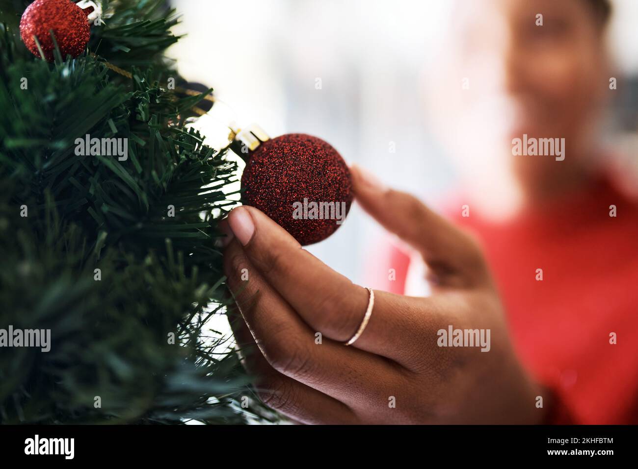 Mano, decorazione con ornamento di Natale e albero, festa di celebrazione zoom con tradizione festosa. Sfera rossa, glitter per albero di Natale con Foto Stock