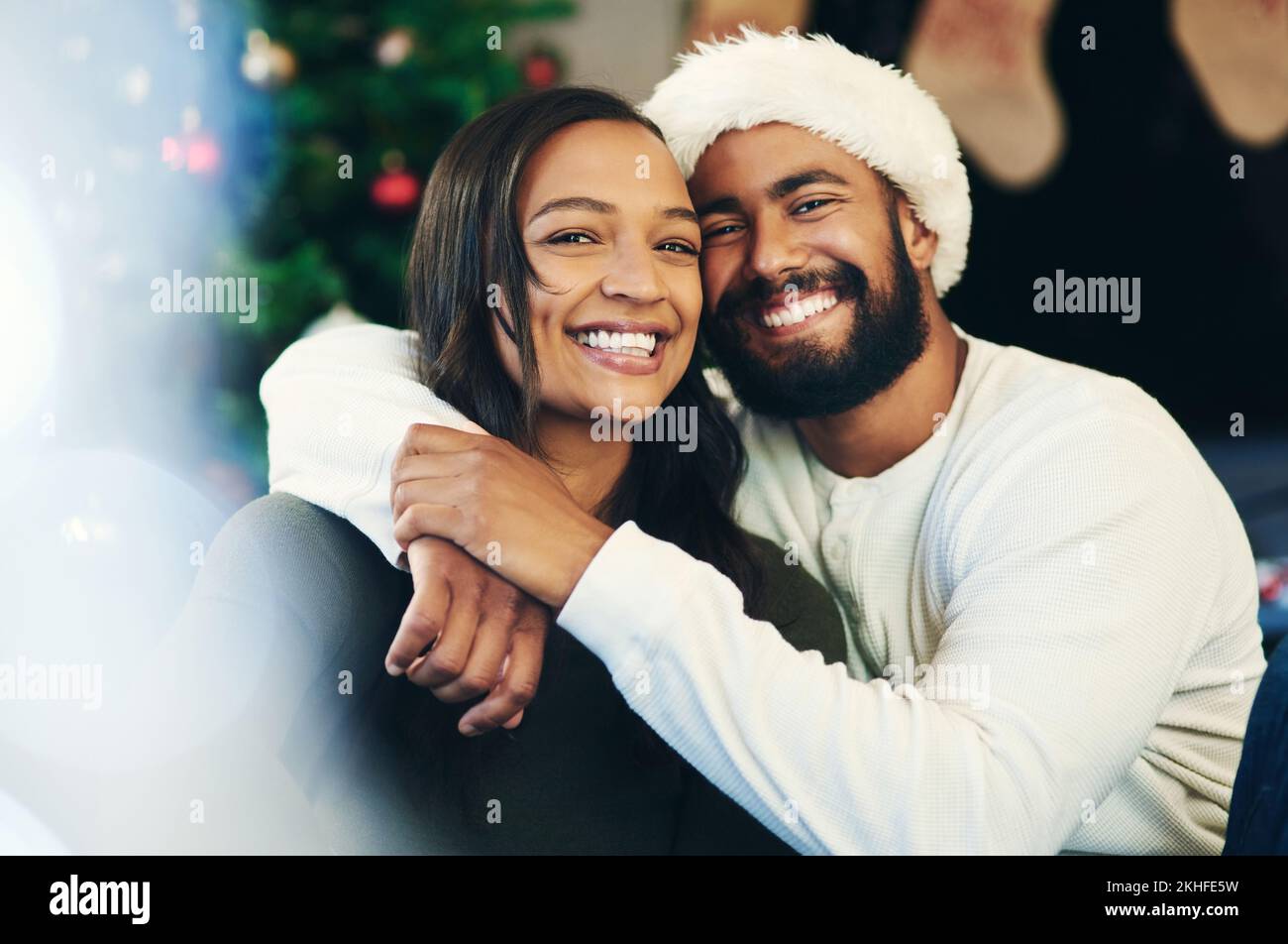 Natale, amore e ritratto di coppia abbraccio in celebrazione di una vacanza cristiana inverno in casa soggiorno. Relax, matrimonio e felice donna gode Foto Stock