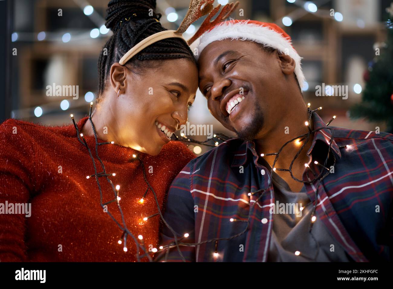 Coppia, festa di natale e festa, luci e sorriso felice, cappello e amore insieme con la decorazione della casa. Uomo nero, donna o felicità Foto Stock