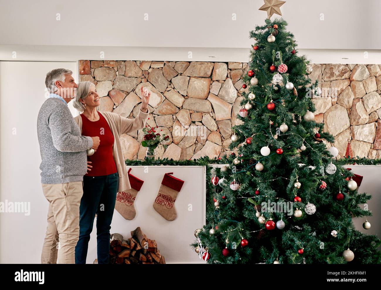 Donna anziana e uomo, albero di natale decorazione con pianificazione, parlare o discussione in casa. Coppia anziana, decorazione interna e vacanza Foto Stock