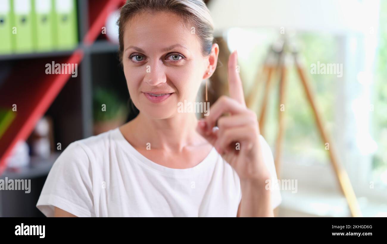 Donna sorridente che guarda la macchina fotografica e indica con l'indice Foto Stock