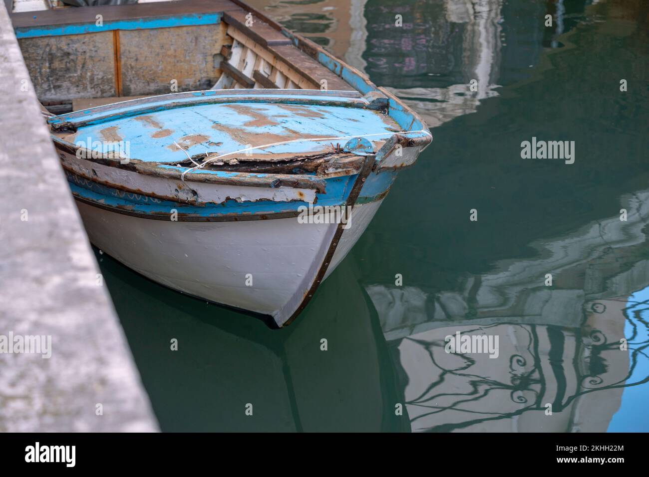 vecchia barca di legno vicino al molo di cemento Foto Stock