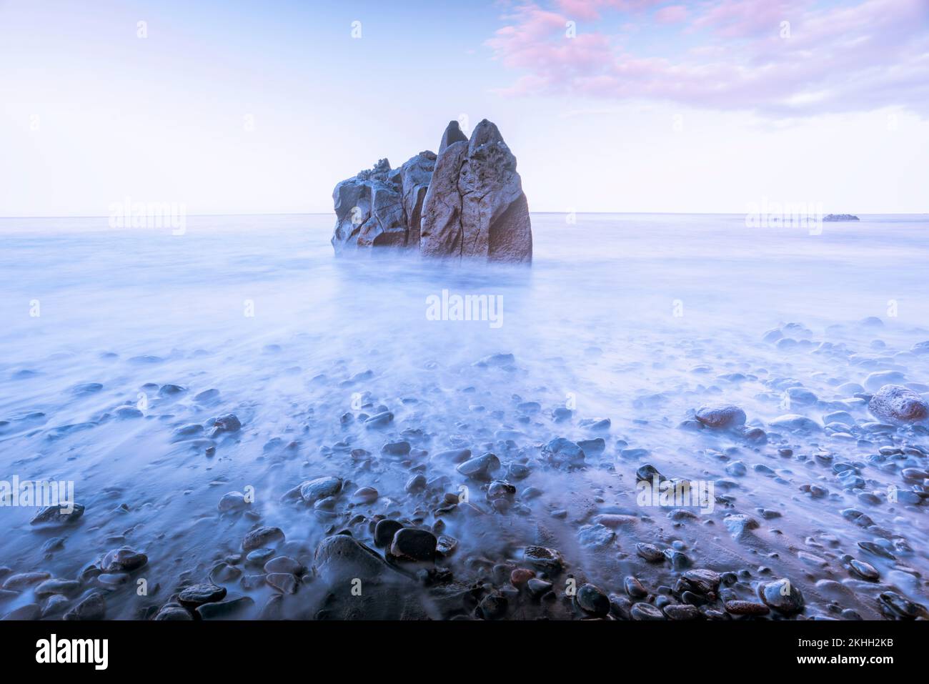 spiaggia di ciottoli vuota all'alba con formazione rocciosa sullo sfondo Foto Stock