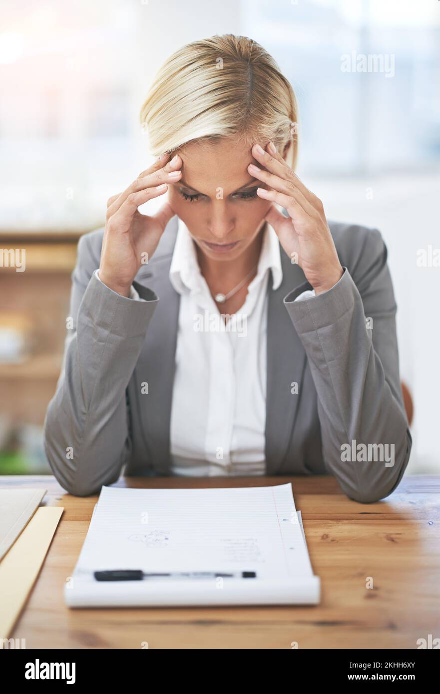 Alcuni giorni sono solo un grande mal di testa ... una donna d'affari seduta alla sua scrivania guardando stressato. Foto Stock