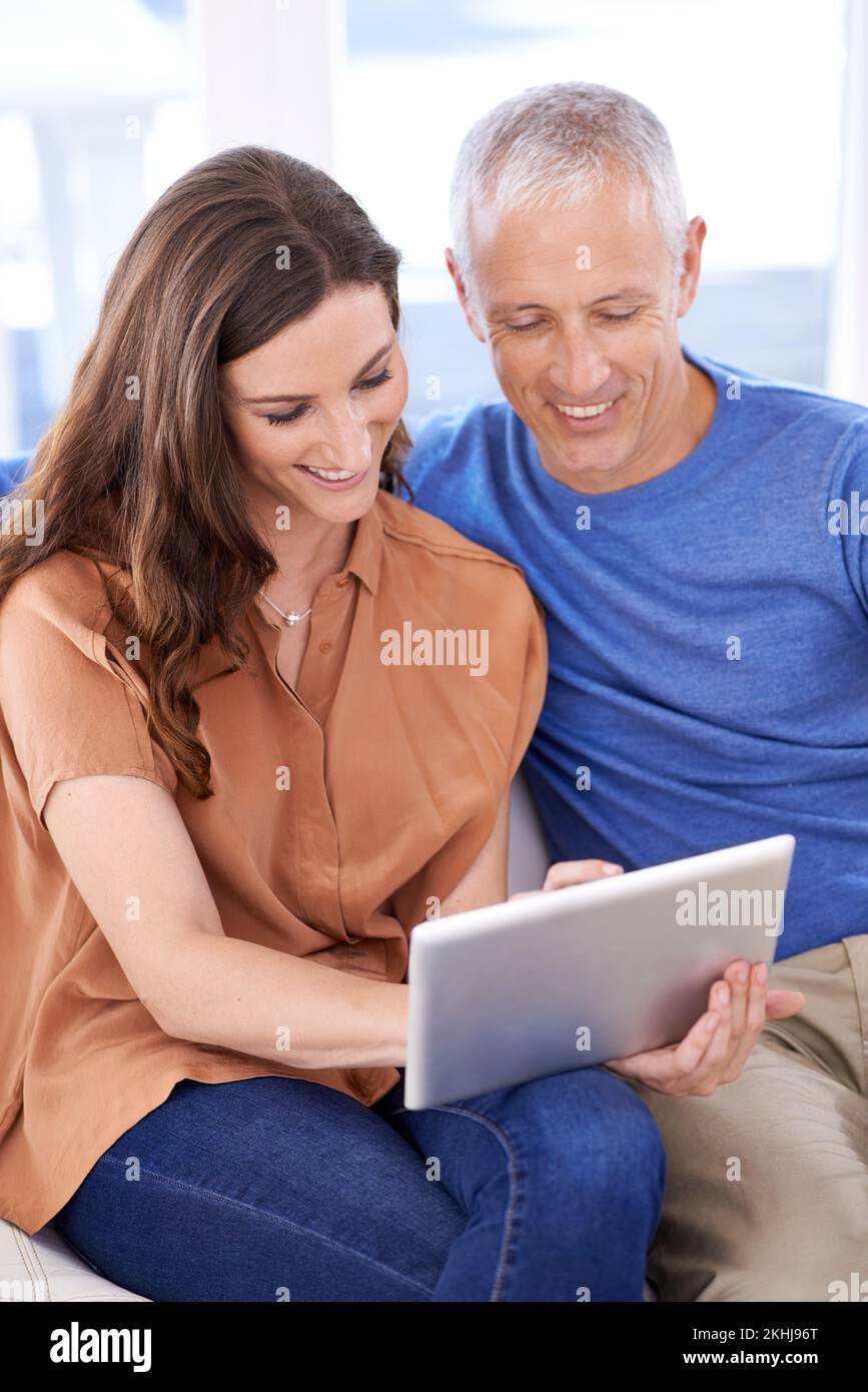 Condividono gli stessi interessi online. una coppia felice a casa utilizzando il tablet digitale insieme. Foto Stock