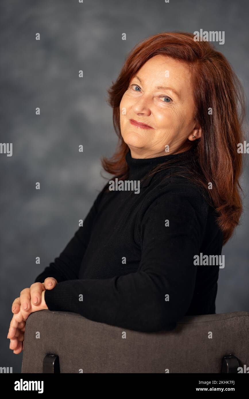 Ritratto di elegante donna di 60s anni su sfondo grigio. Donna matura di mezza età, elegante e sicura in europa Foto Stock