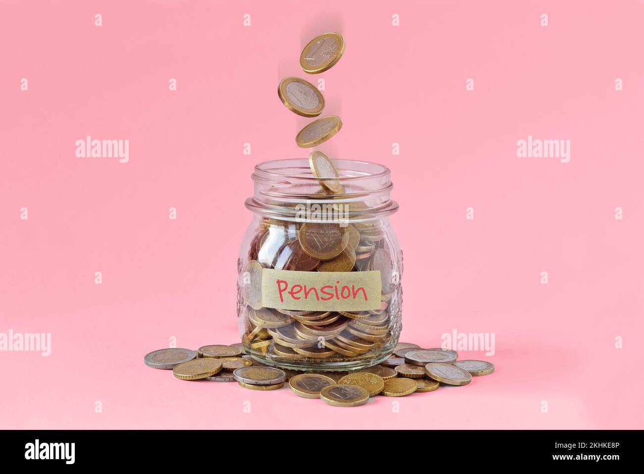 Barattolo con etichetta con la parola pensione e monete in caduta su sfondo rosa - concetto di donne e pensione Foto Stock