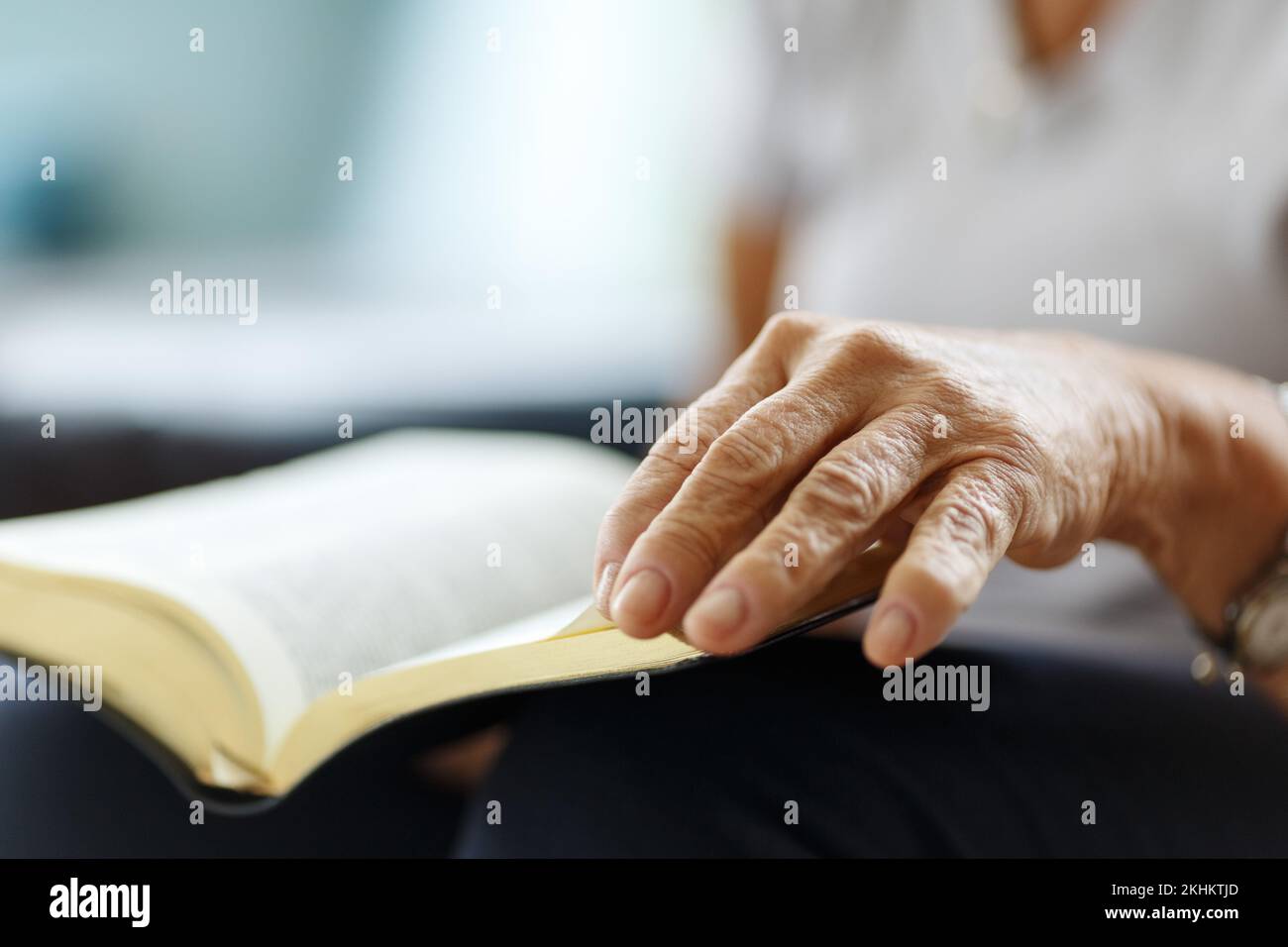Primo piano delle mani della donna anziana sulla bibbia, ripiegato in preghiera Foto Stock