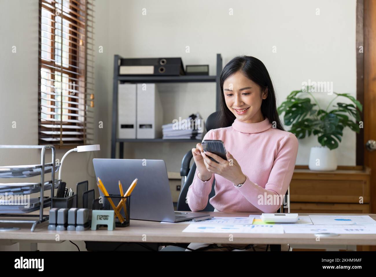 Le giovani donne asiatiche lavorano con documenti finanziari a casa contare su calcolatrice prima di pagare le ricevute fiscali online per telefono. Donna che progetta millennial Foto Stock