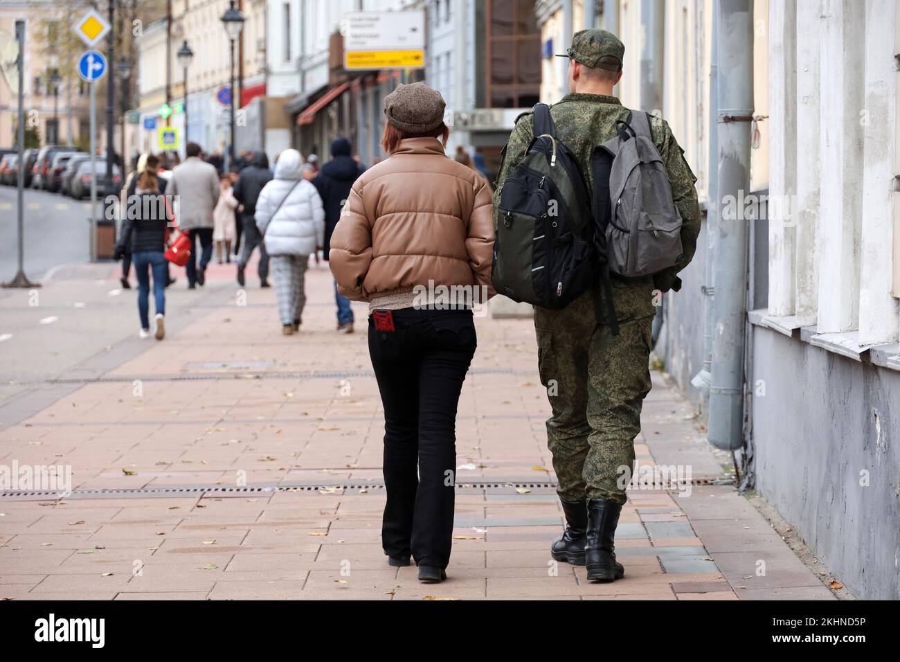 Ragazza con soldato di forze militari in mimetizzazione camminando lungo la strada della città in autunno Foto Stock