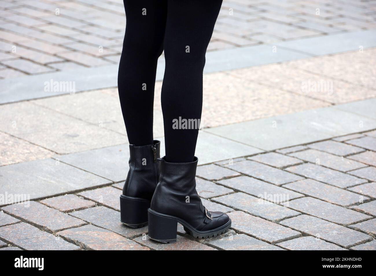 Gambe femminili in caldo collant nero e scarpe con tacchi alti. Ragazza in piedi su una strada, la moda nella città d'autunno Foto Stock