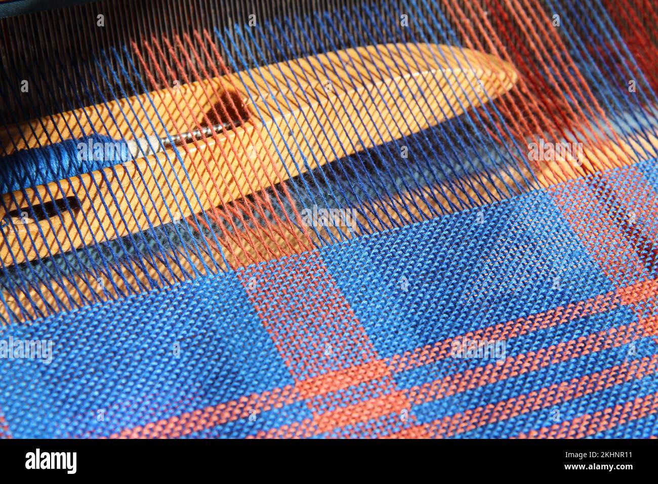Tessitura a navetta in un telaio da tavola, tessitura a tela con filo di cotone in blu e arancione. Foto Stock
