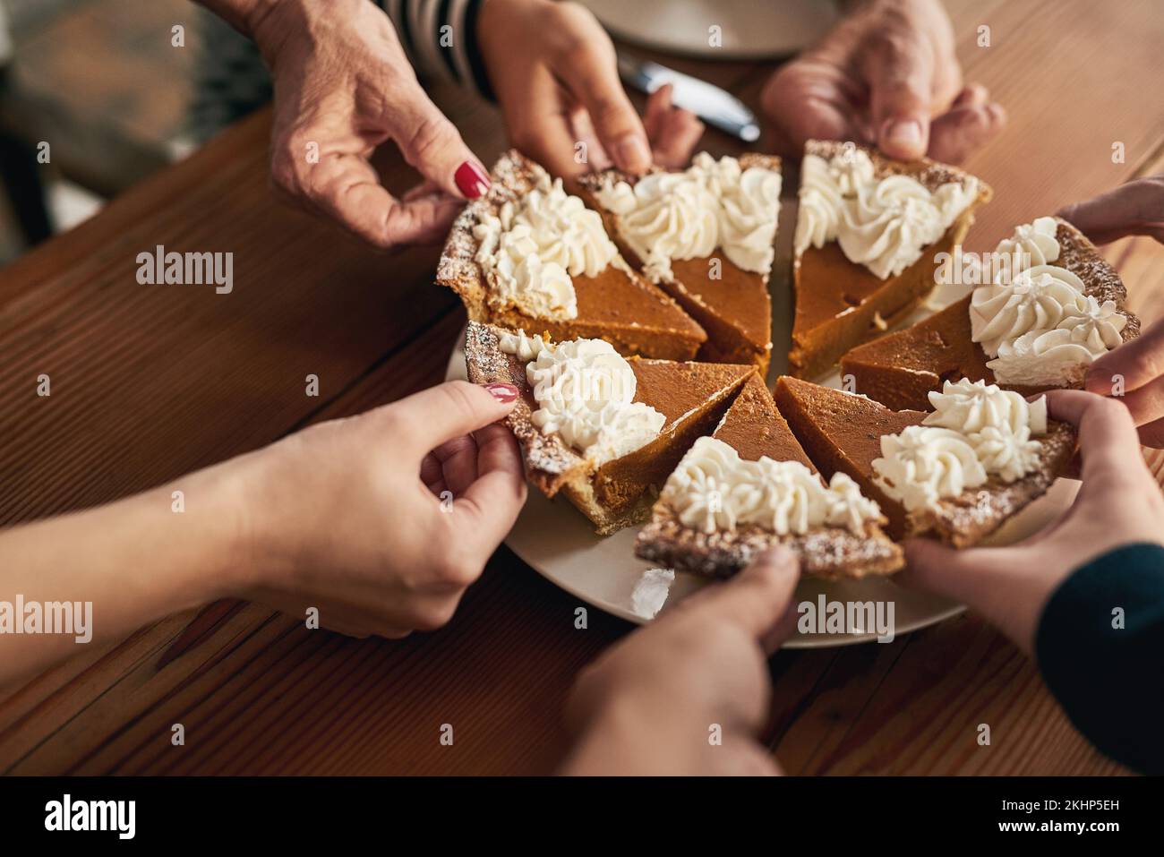 Festa, torta di zucca e mani di persone a tavola per il ringraziamento, la celebrazione e le feste. Cibo, dessert e comunità con la famiglia e la cena Foto Stock