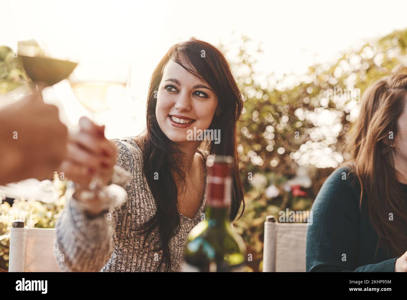 Brindisi, festa e donna con un bicchiere di vino a pranzo in famiglia in un giardino per Natale. Festeggiamenti, festa e ragazza con un drink di alcol, bicchiere di vino Foto Stock