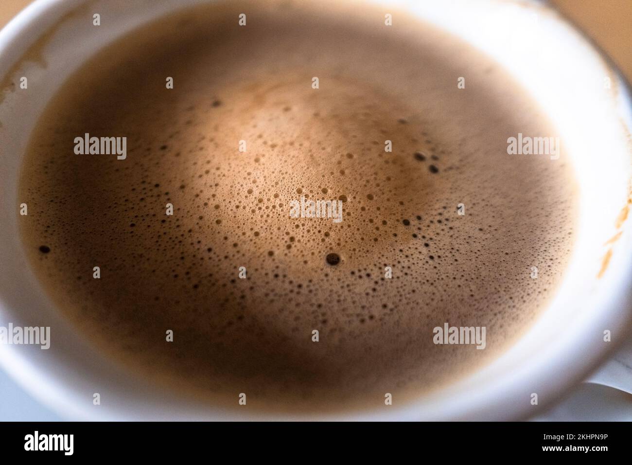 Un primo piano delle bolle e della schiuma che galleggiano sulla superficie di una tazza di caffè. Foto Stock