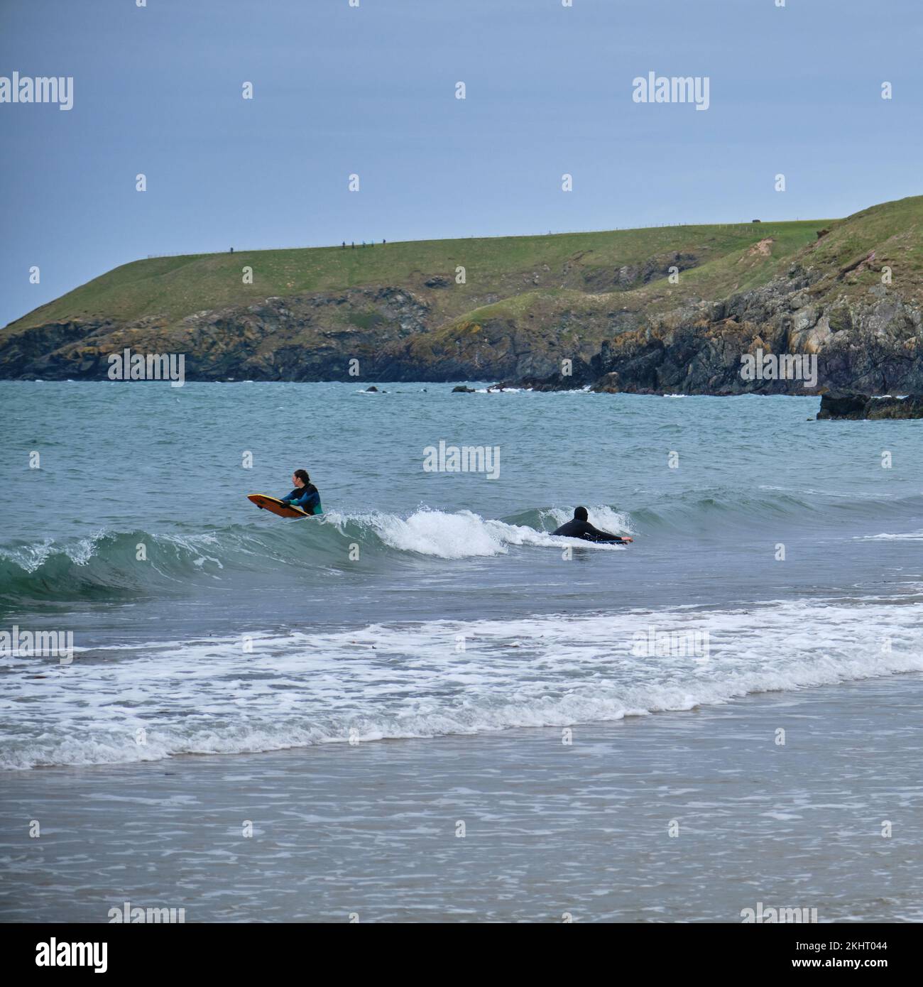 Una coppia di bodyboarding sulle spiagge fischianti a Porthor, Galles Foto Stock