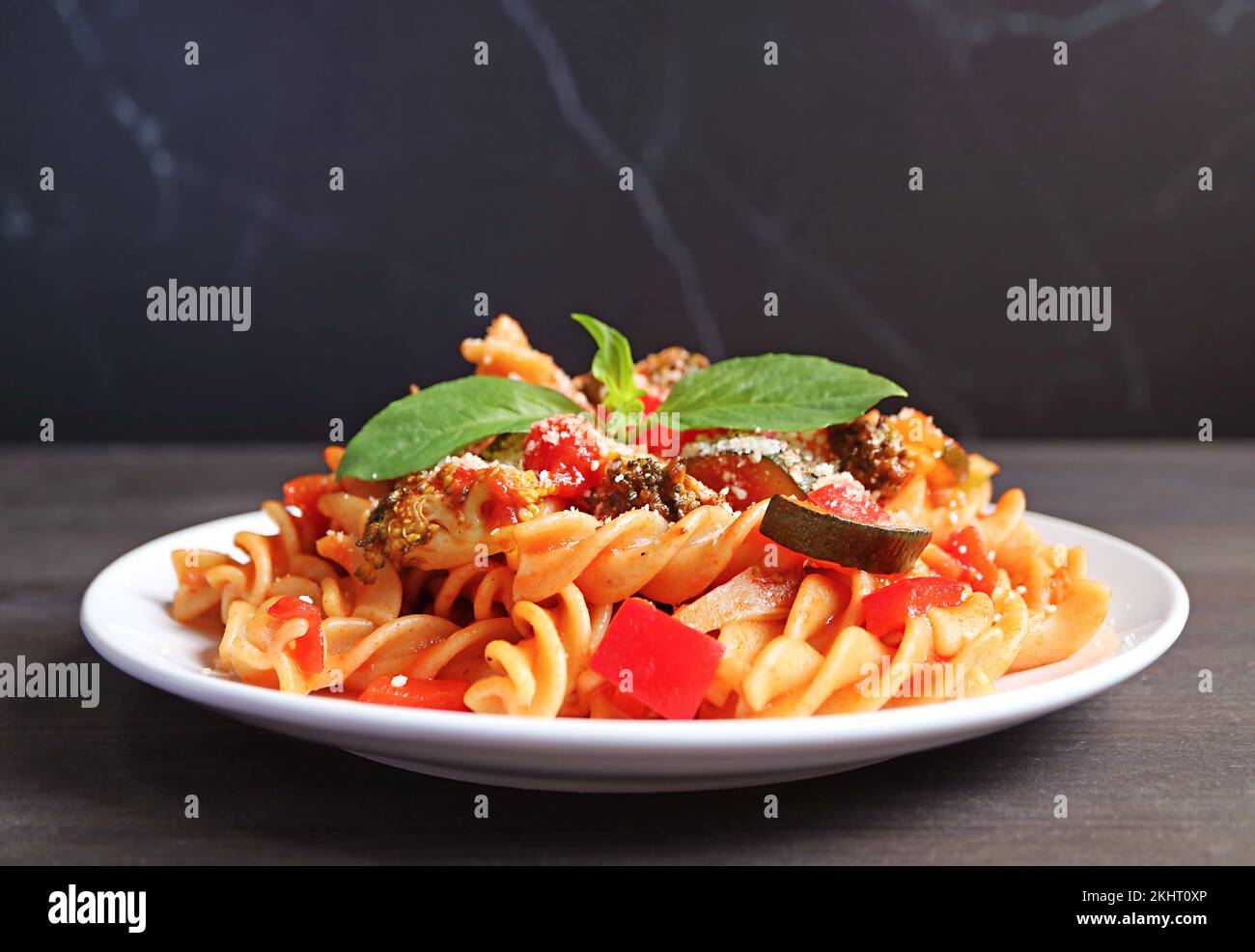 Un piatto di succulenta pasta Fusilli integrale in salsa di pomodoro su sfondo nero Foto Stock