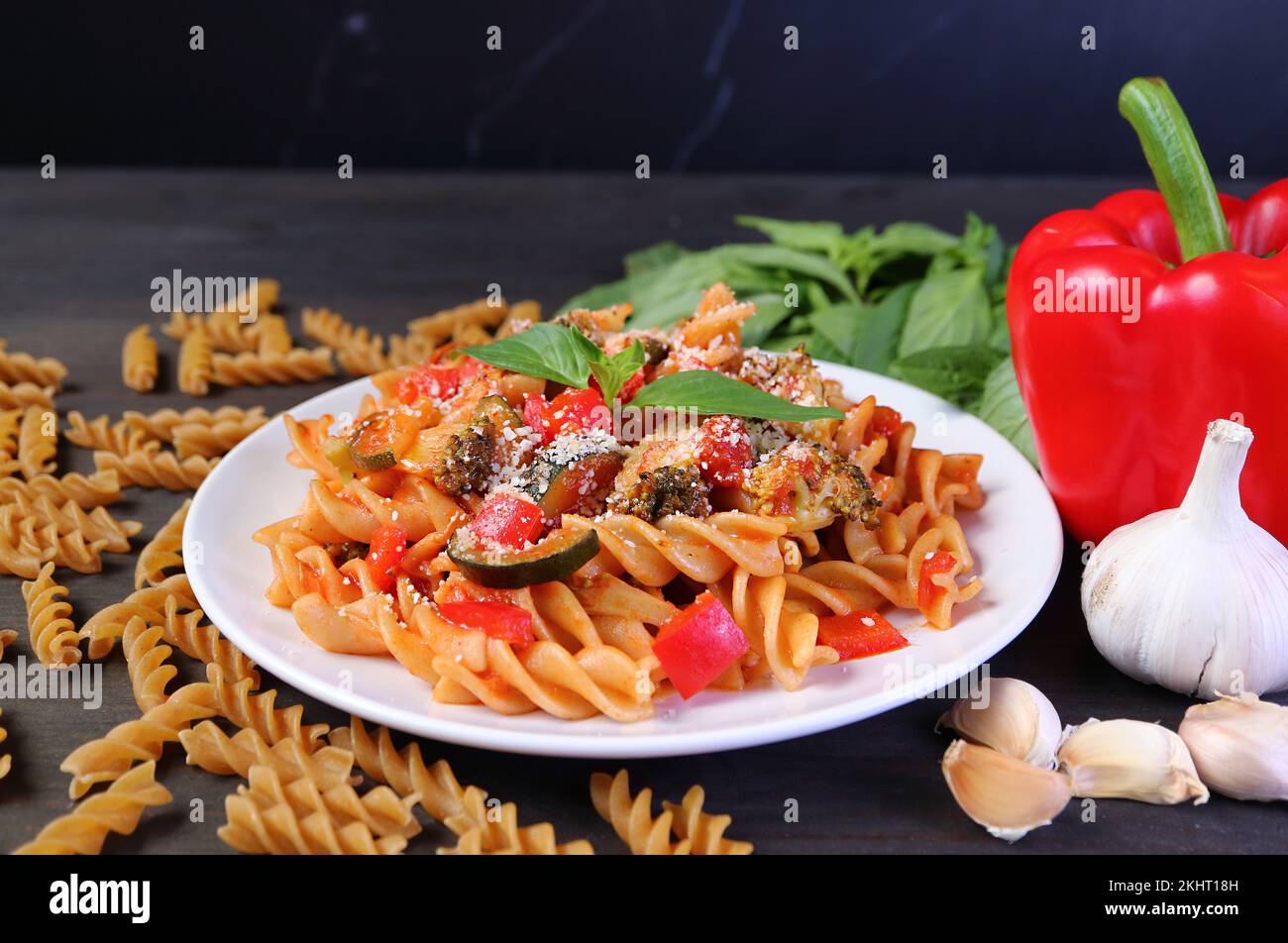 Fusilli crudi appena cotti in salsa di pomodoro sul tavolo da cucina con i suoi ingredienti Foto Stock