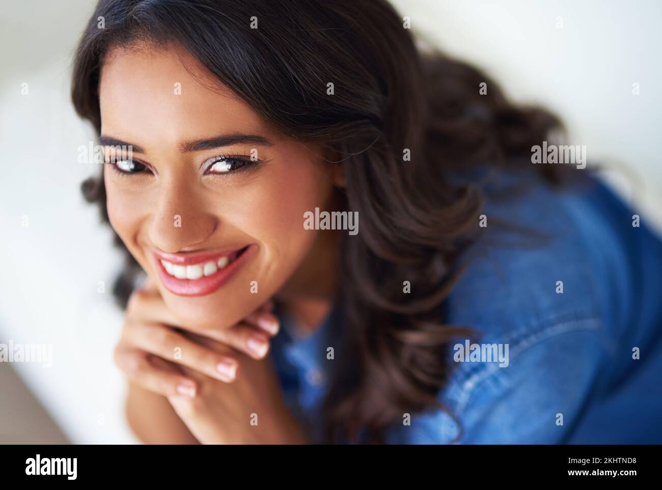 Donna, viso e felice di rilassarsi ritratto sul divano a casa per la felicità o lo stile di vita rilassante. Giovane, sorriso e salute mentale benessere o. Foto Stock