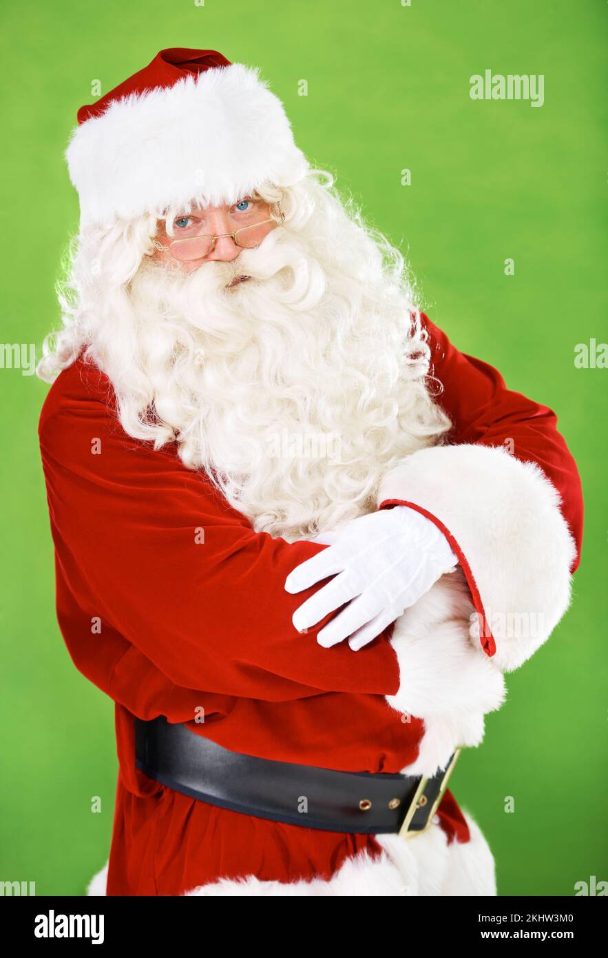 Natale, babbo natale e costume con un uomo in studio su uno sfondo verde per la celebrazione di stagione festiva. Ritratto, occhiali e atteggiamento serio di Foto Stock
