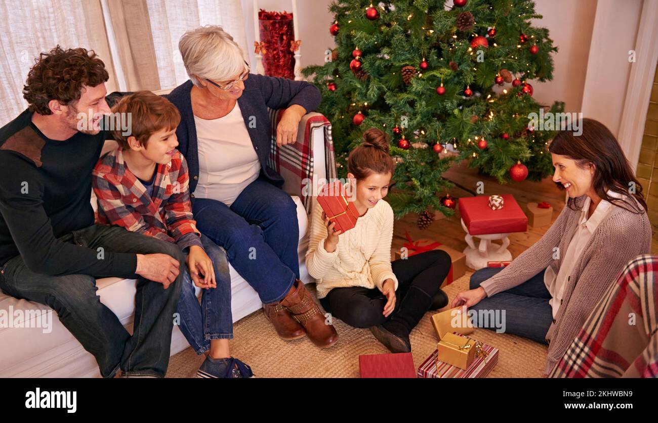 Natale, famiglia e regalo aperto nella sala, felice e sorridere insieme per la stagione festiva. Natale, nonna e genitori con figli, doni e. Foto Stock