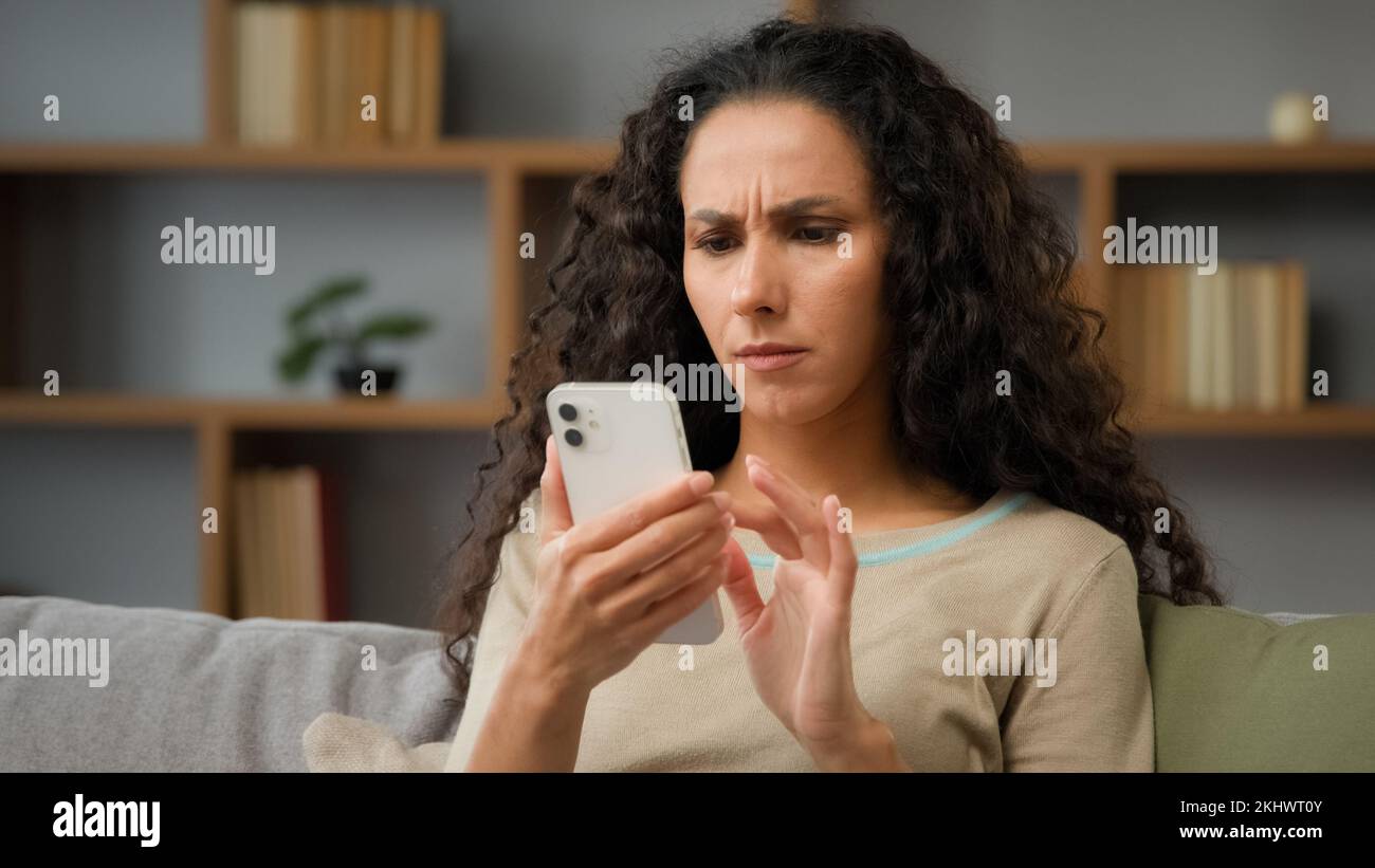 Closeup arrabbiato confuso sconcertato stressato nervoso donna adulta guardando lo schermo del cellulare a casa ha problemi con la connessione wi-fi sensazione frustrato di Foto Stock