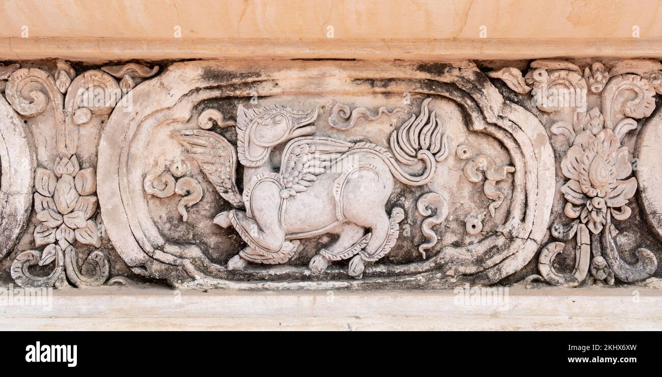 Antico pannello di scultura stucco di animali mitologici con ali sulla parete della biblioteca di hor trai nel tempio buddista di Wat Phra Singh, Chiang mai, Thailandia Foto Stock