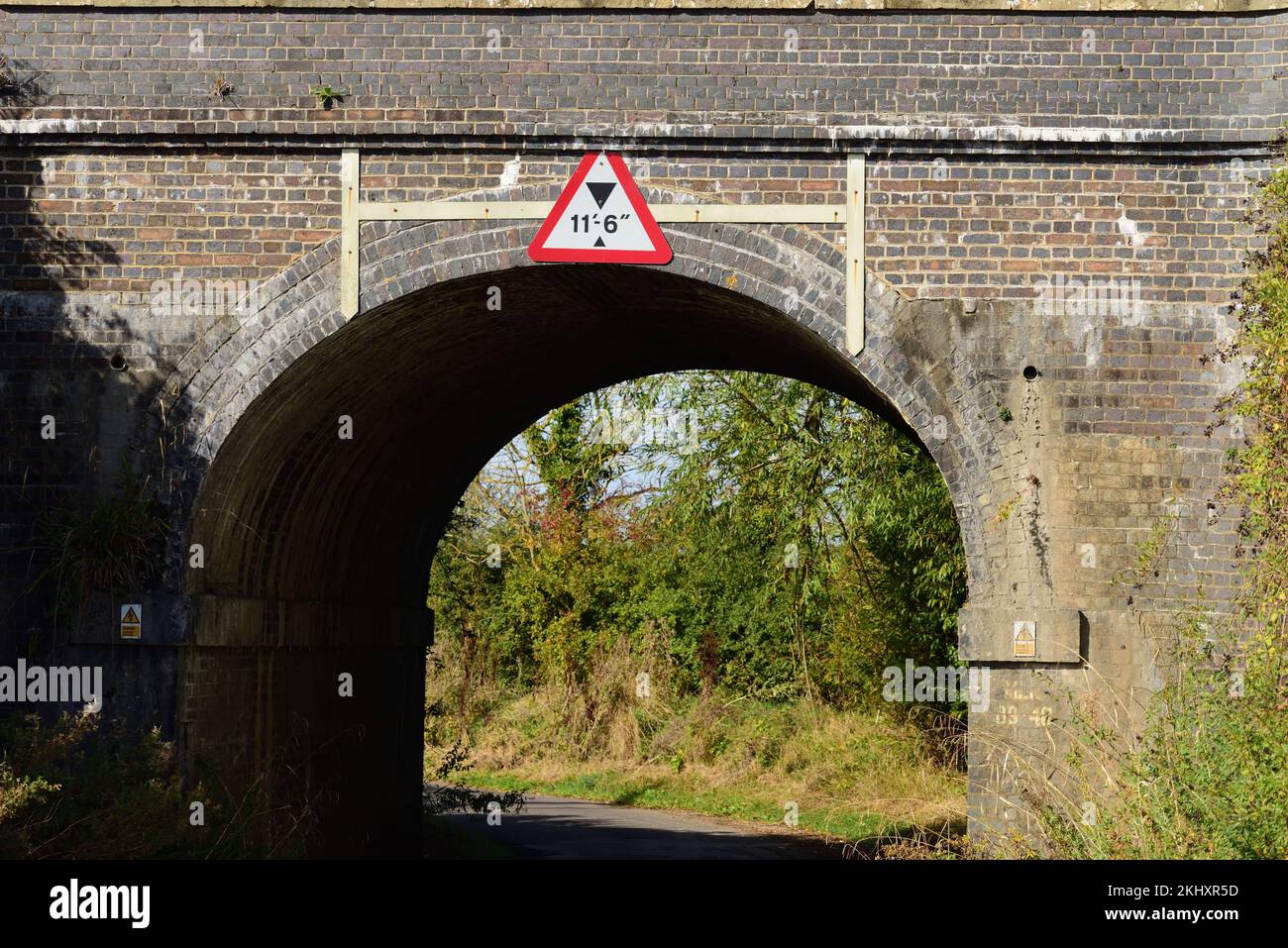 Un ponte ferroviario con spazio limitato su una stretta corsia di campagna. Foto Stock