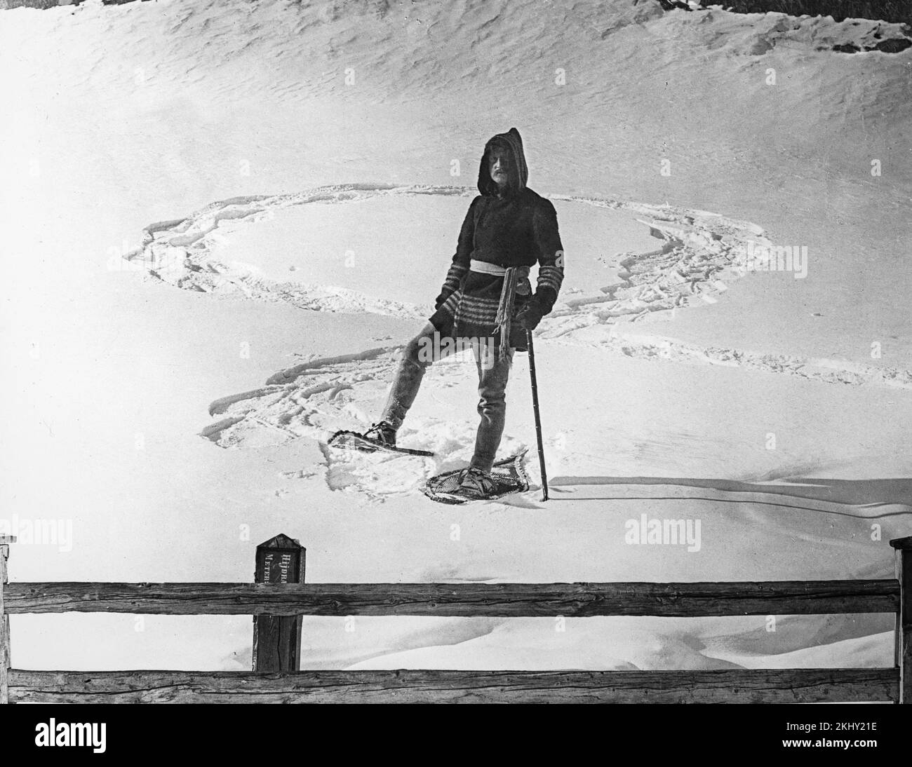 Una fotografia in bianco e nero dei primi anni del 20th che mostra un uomo che indossa scarpe da neve e abiti caldi che posa su una zona innevata nelle Alpi francesi. Foto Stock