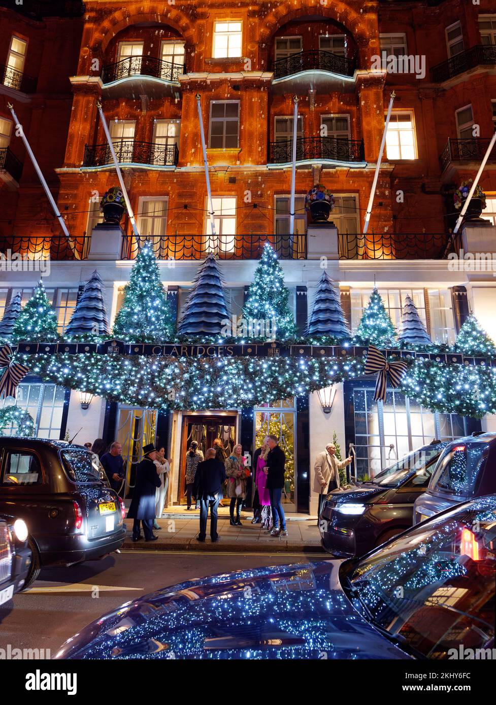 L'iconica facciata dell'hotel di Claridge, con esposizione natalizia. Gli ospiti aspettano un taxi con il portiere fuori dall'ingresso. Foto Stock