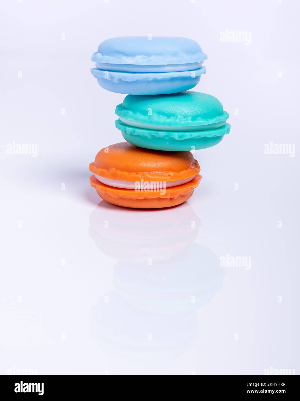 Tre macaron di tre colori diversi impilati in modo non simmetrico, su sfondo bianco Foto Stock