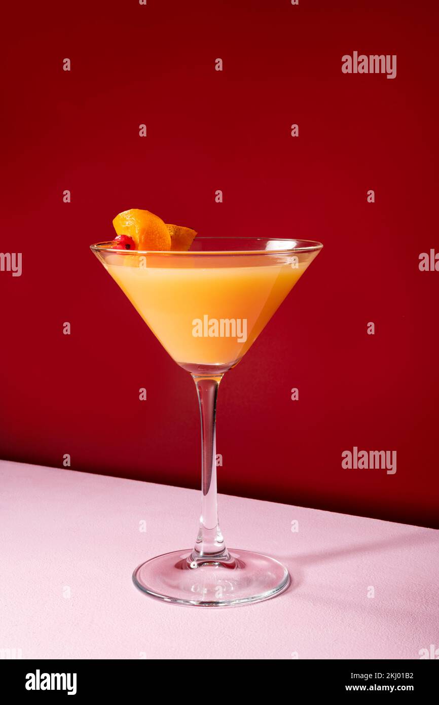 Vodka con cocktail di succo d'arancia guarnita con buccia d'arancia sul rosso scuro Foto Stock