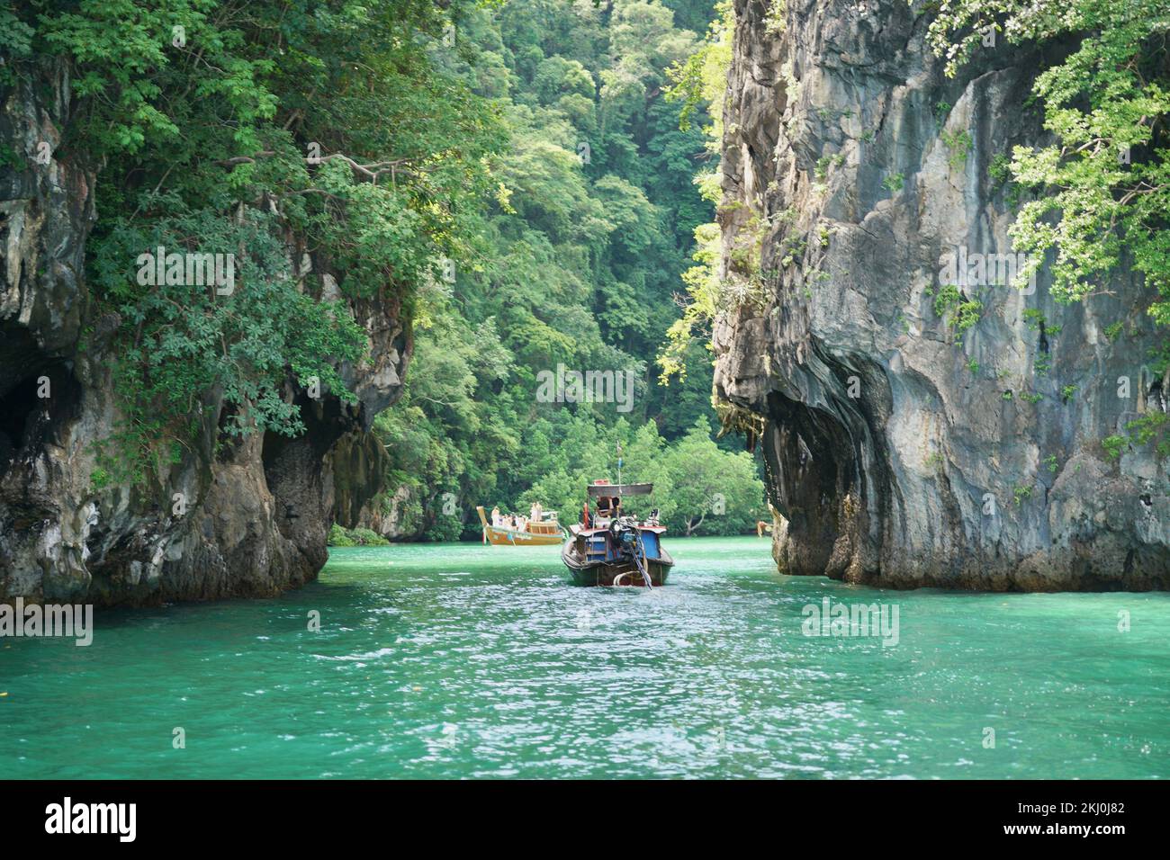 Una barca tra scogliere rocciose boscose a Krabi, Thailandia Foto Stock