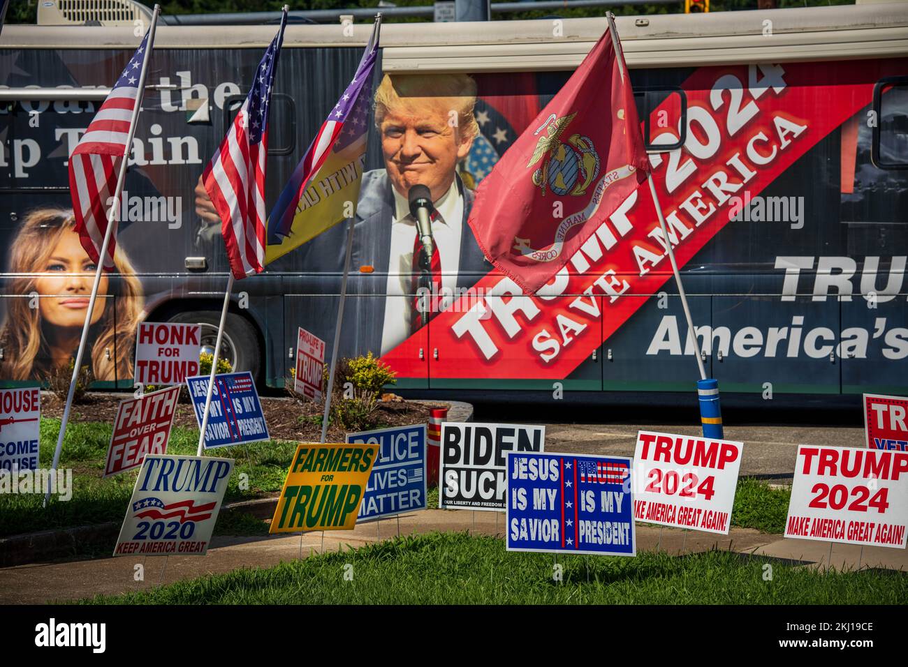 Molte bandiere e cartelli americani davanti a un autobus elettorale con foto di Trump e Melania Foto Stock