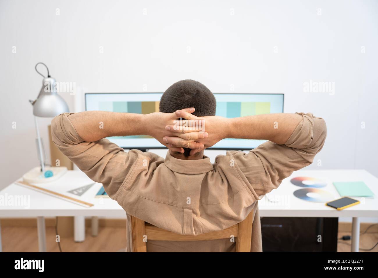 Giovane uomo bello che lavora da casa su un computer desktop. Creative Designer si è rilassato nel suo set di lavoro. Foto Stock