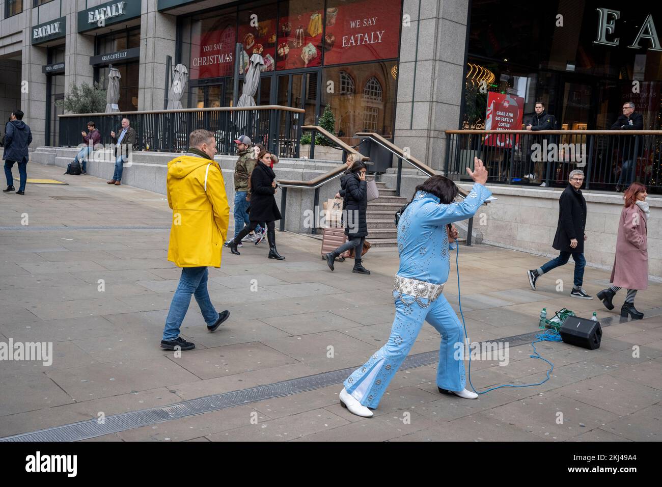 Il 24th novembre 2022, a Londra, in Inghilterra, un atto di tributo simile a quello di Elvis Presley rappresenta il Re davanti al passaggio di pendolari alla stazione di Liverpool Street nella City of London, il quartiere finanziario della capitale. Foto Stock