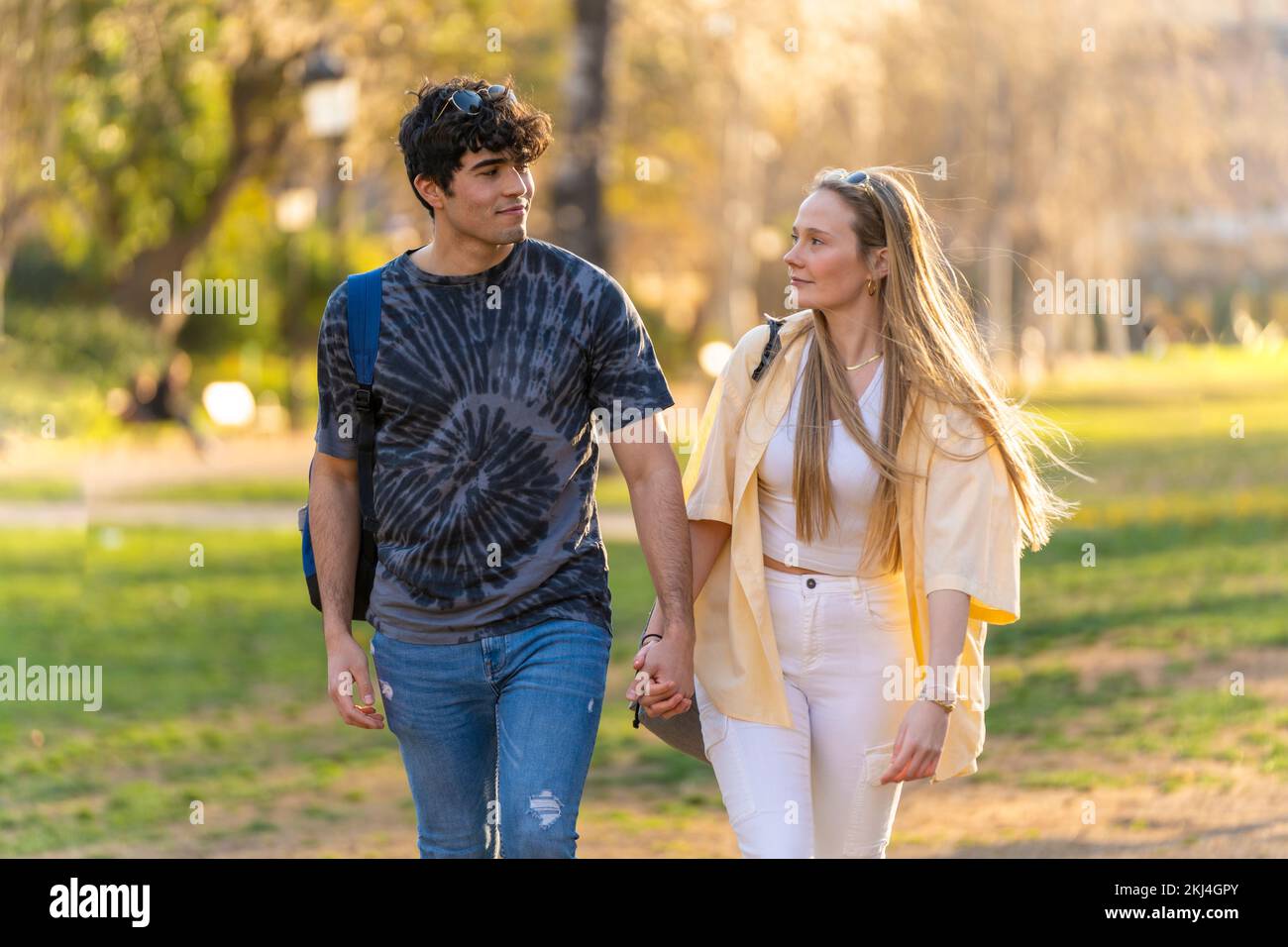 Giovane coppia eterosessuale che cammina in un parco e si guarda l'un l'altro Foto Stock