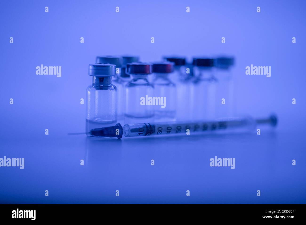 Flaconcino di vaccino, siringa con ago per iniezione influenzale, concetto medico di vaccinazione, iniezione sottocutanea su sfondo blu. Spazio di copia. Test di immunizzazione e. Foto Stock