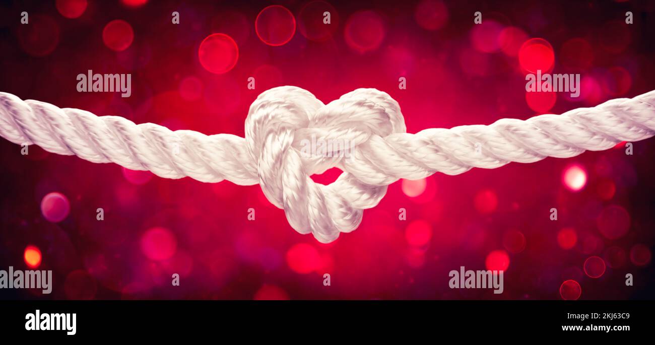 Corda bianca con cuore a forma di nodo su sfondo Bokeh rosso - legatura il nodo - matrimonio e concetto di San Valentino Foto Stock